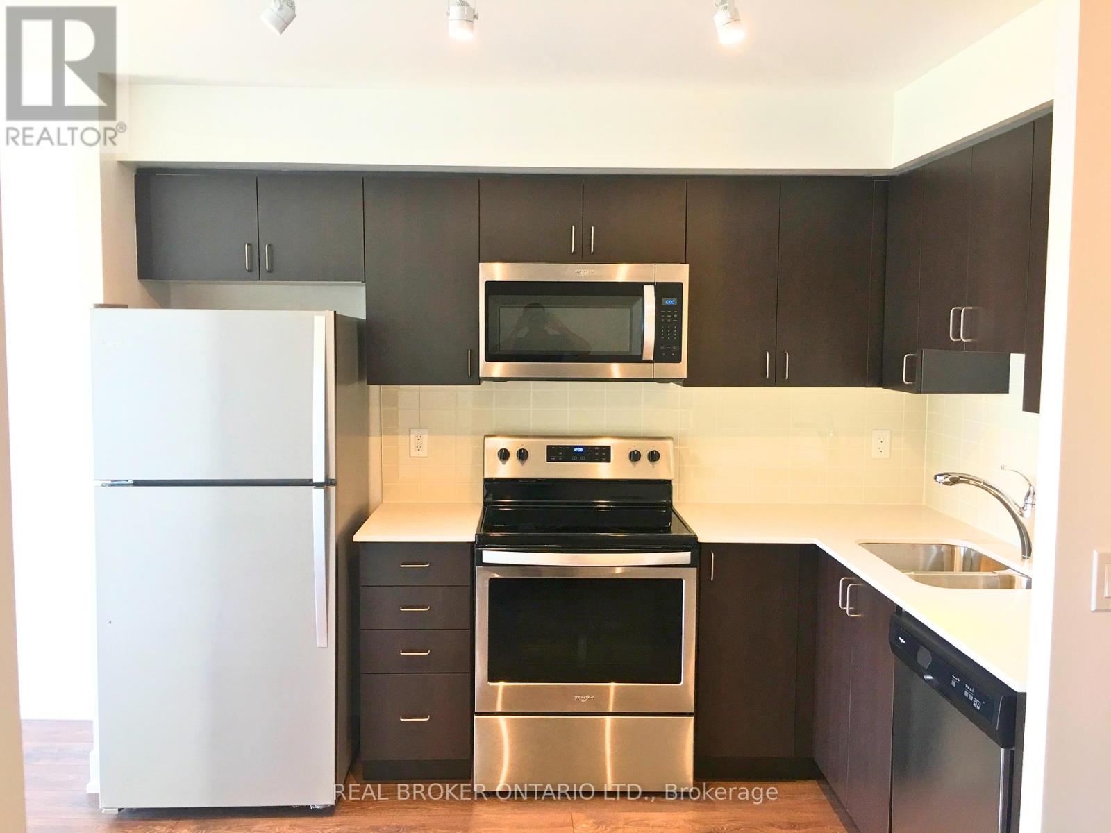 A kitchen with a white fridge, stainless steel oven, microwave, and dishwasher.