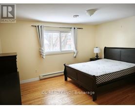A bedroom with a bed, nightstand, and window.