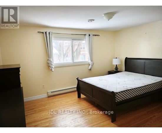 A bedroom with a bed, nightstand, and window.