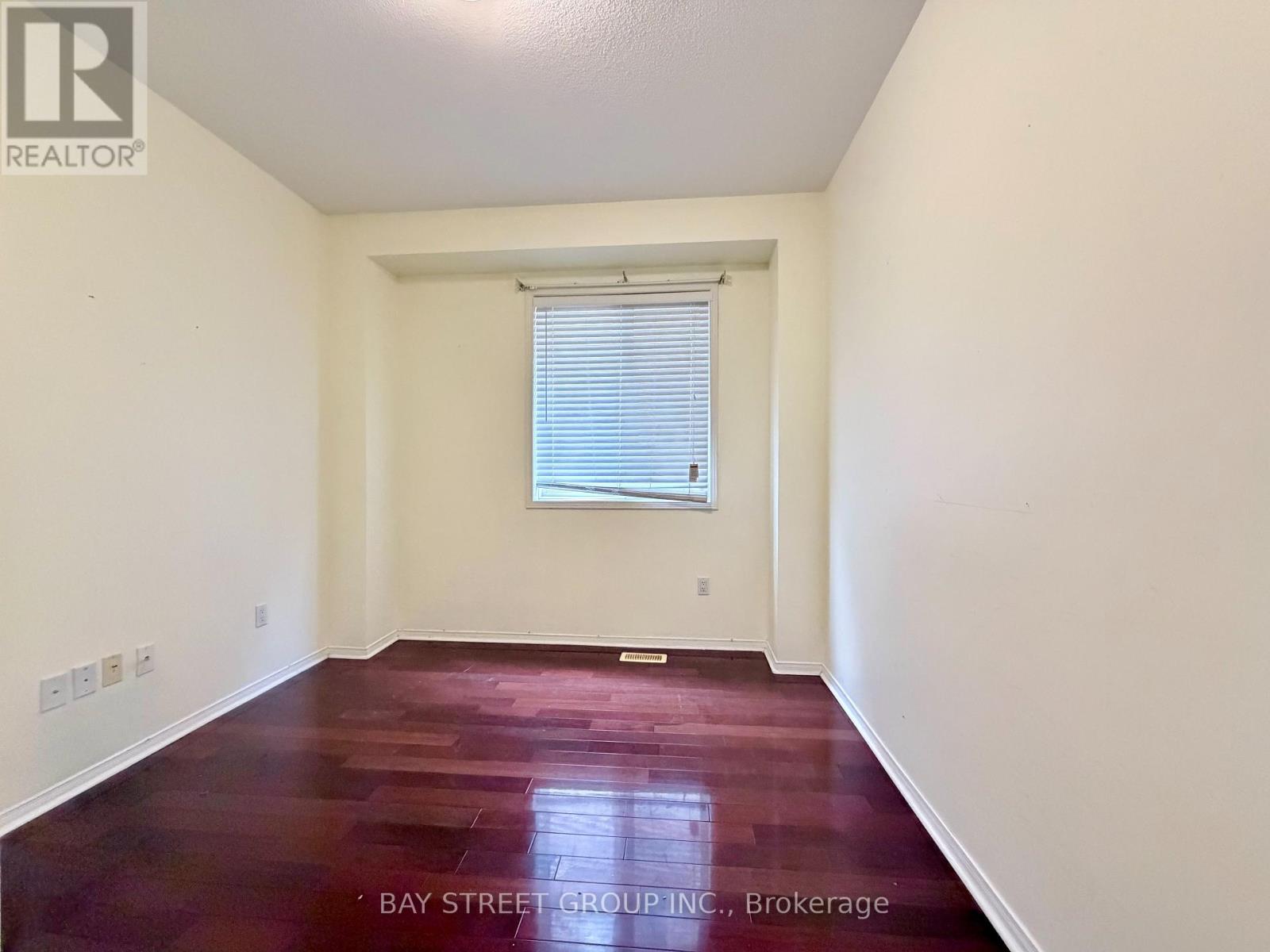 A bedroom with a bed, desk, and window.