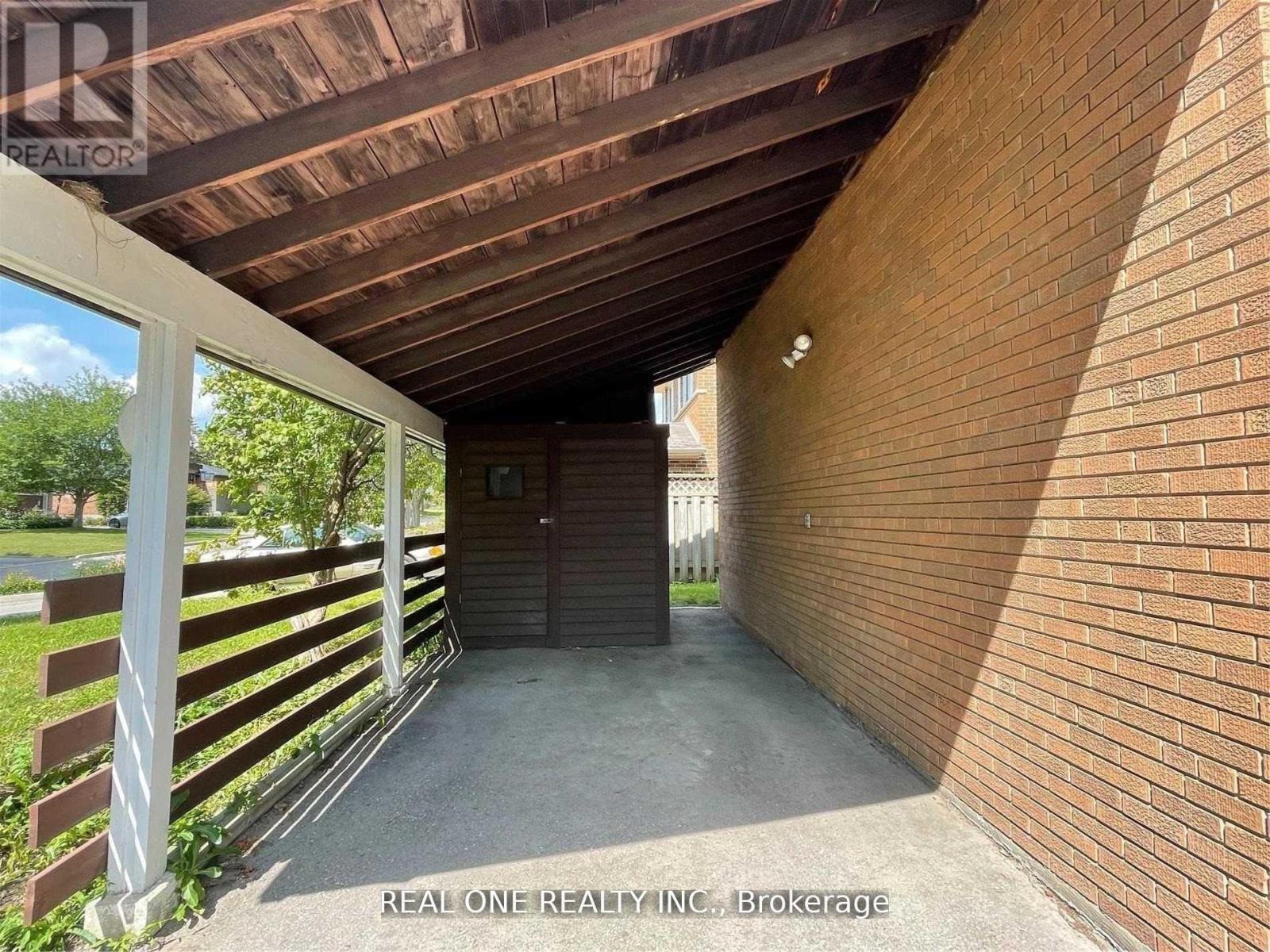 A covered walkway with a wooden ceiling and brick walls.