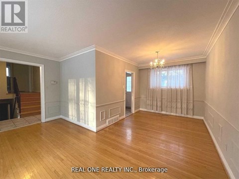A spacious room with wooden floors and a chandelier.