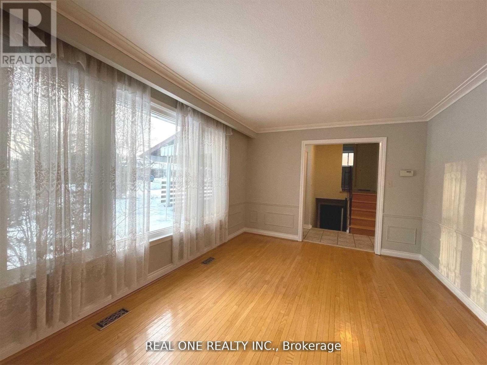 A room with wooden floors and a window with curtains.