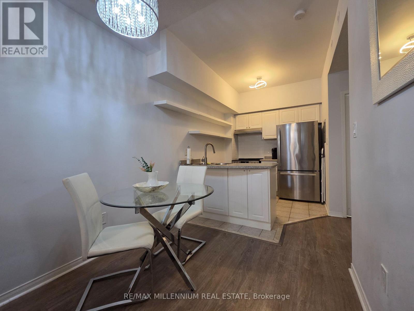 A modern kitchen with a glass table and white chairs.
