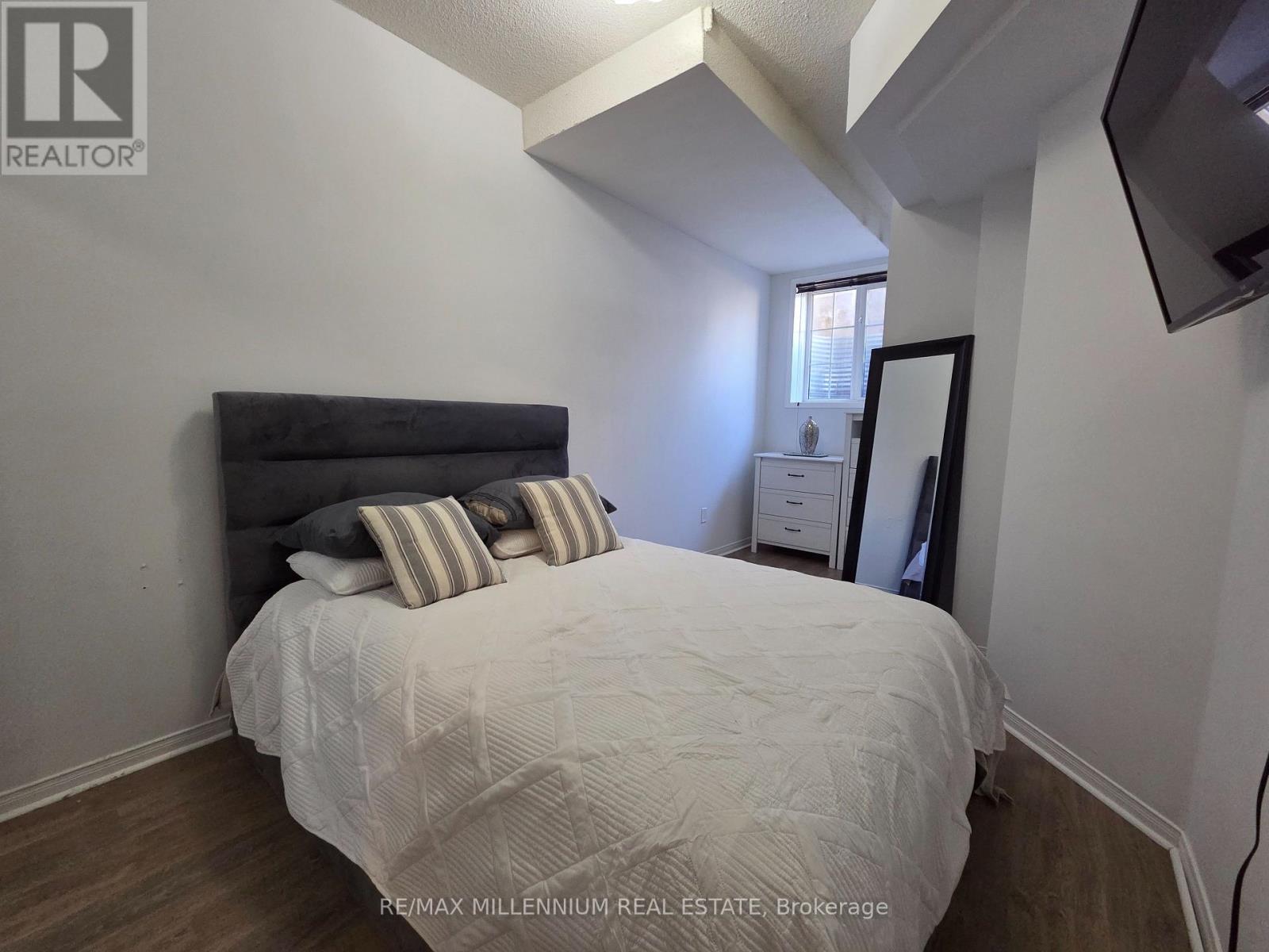 A bedroom with a bed, nightstand, and a mirror.