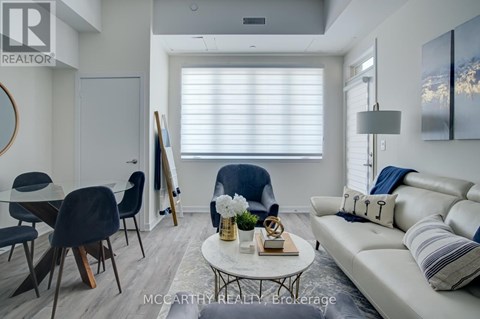 A living room with a white couch, a coffee table, and a painting on the wall.