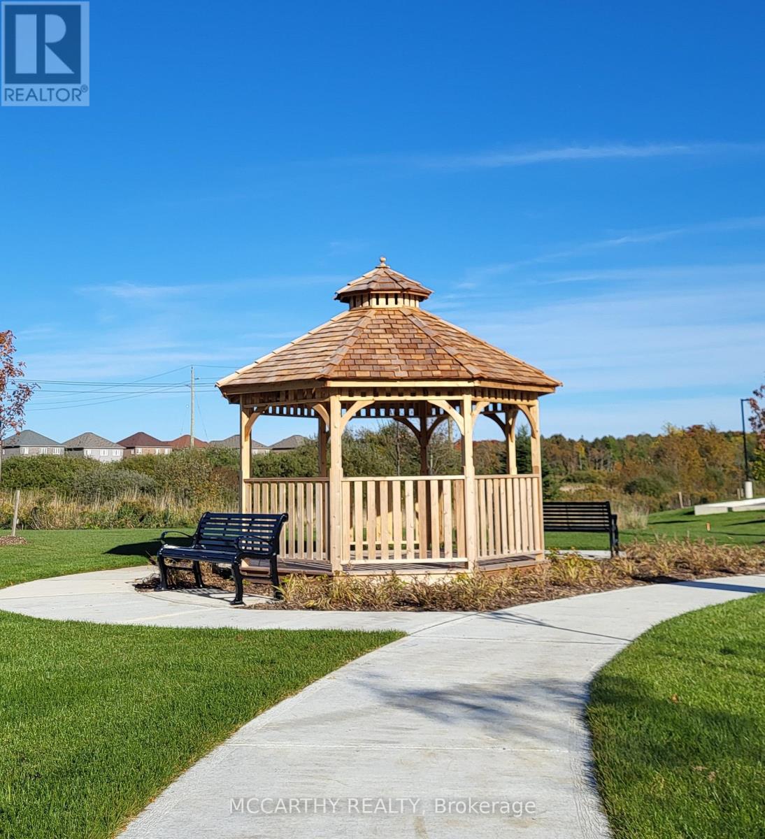 A gazebo with a bench in front of it is situated in a park.
