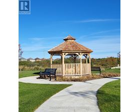 A gazebo with a bench in front of it is situated in a park.