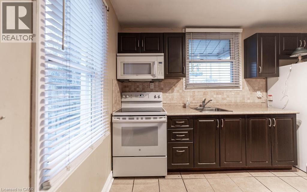 A kitchen with a white microwave and stove, and brown cabinets.