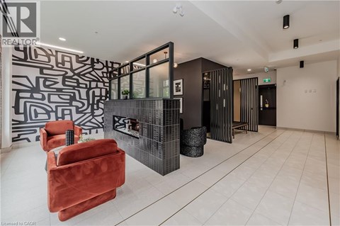 A living room with a red chair and a black and white patterned wall.