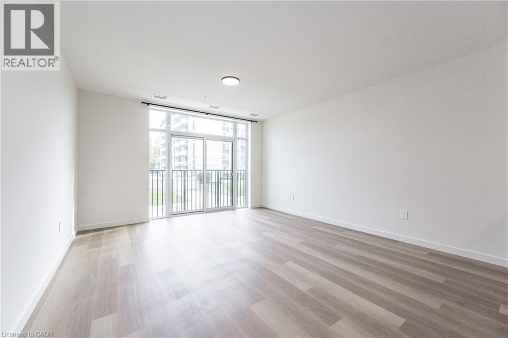 A spacious room with wooden flooring and a sliding glass door.