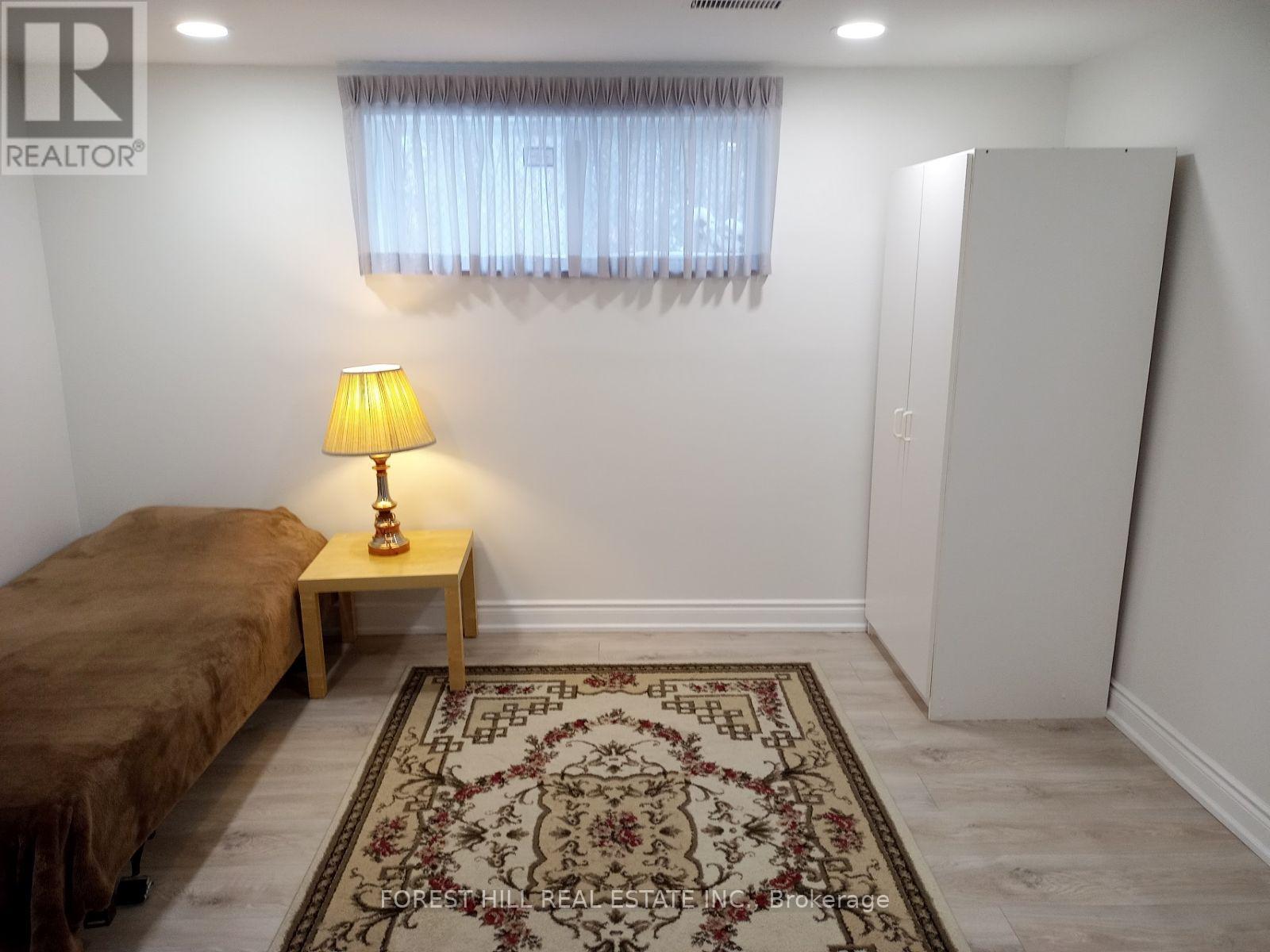 A bedroom with a bed, a lamp, and a rug.