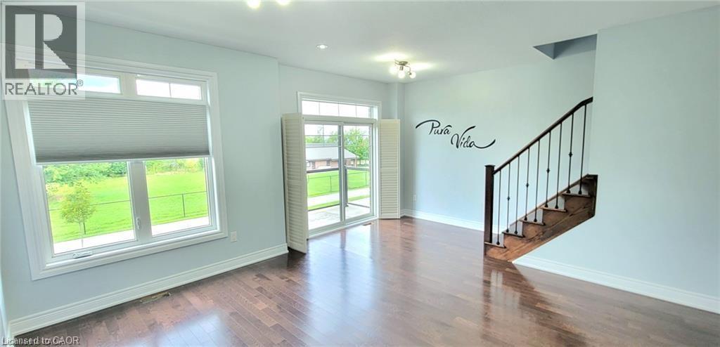 A spacious room with a staircase and a window with blinds.