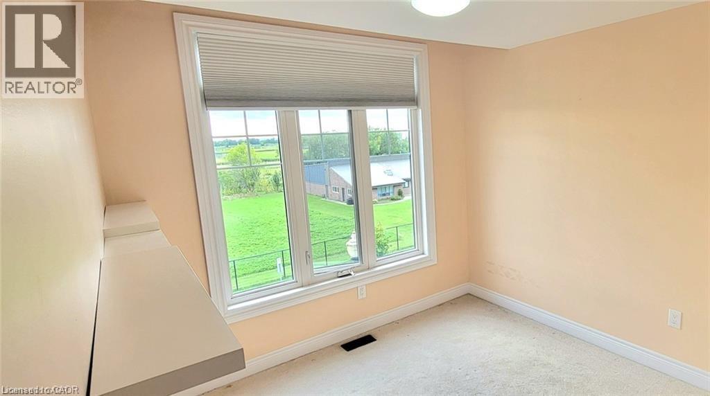 A room with a window that has a view of a green field and a building.