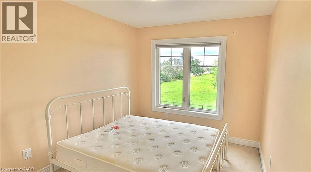 A bedroom with a white bed and a window overlooking a green field.