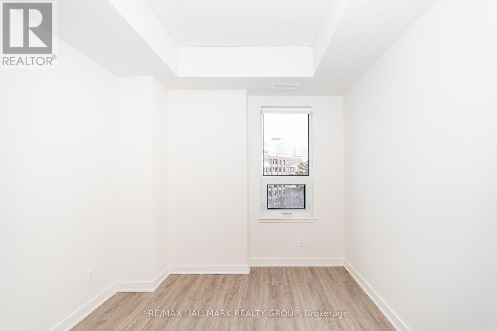 A white room with a picture frame on the wall and a wooden floor.