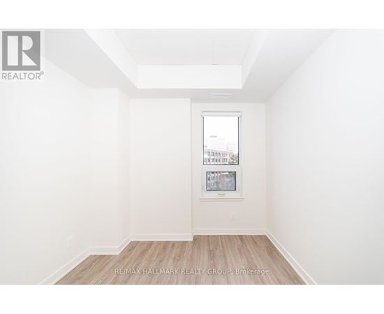 A white room with a picture frame on the wall and a wooden floor.