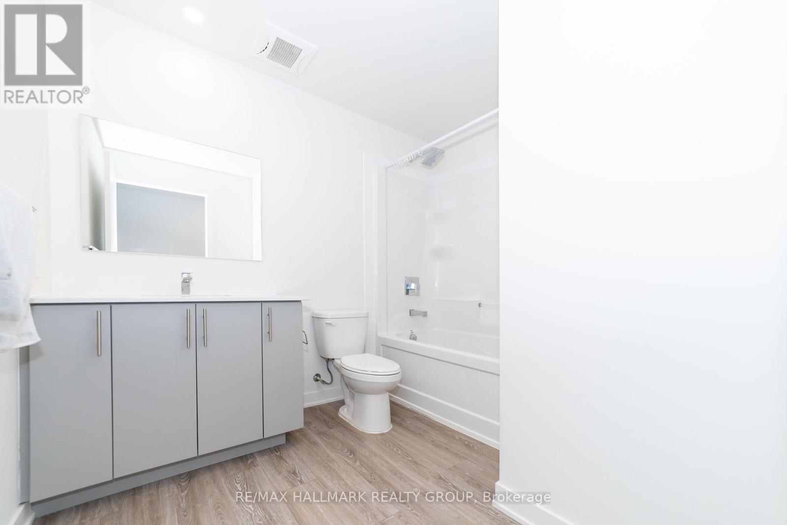 A white bathroom with a toilet, sink, and cabinet.