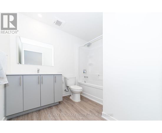 A white bathroom with a toilet, sink, and cabinet.