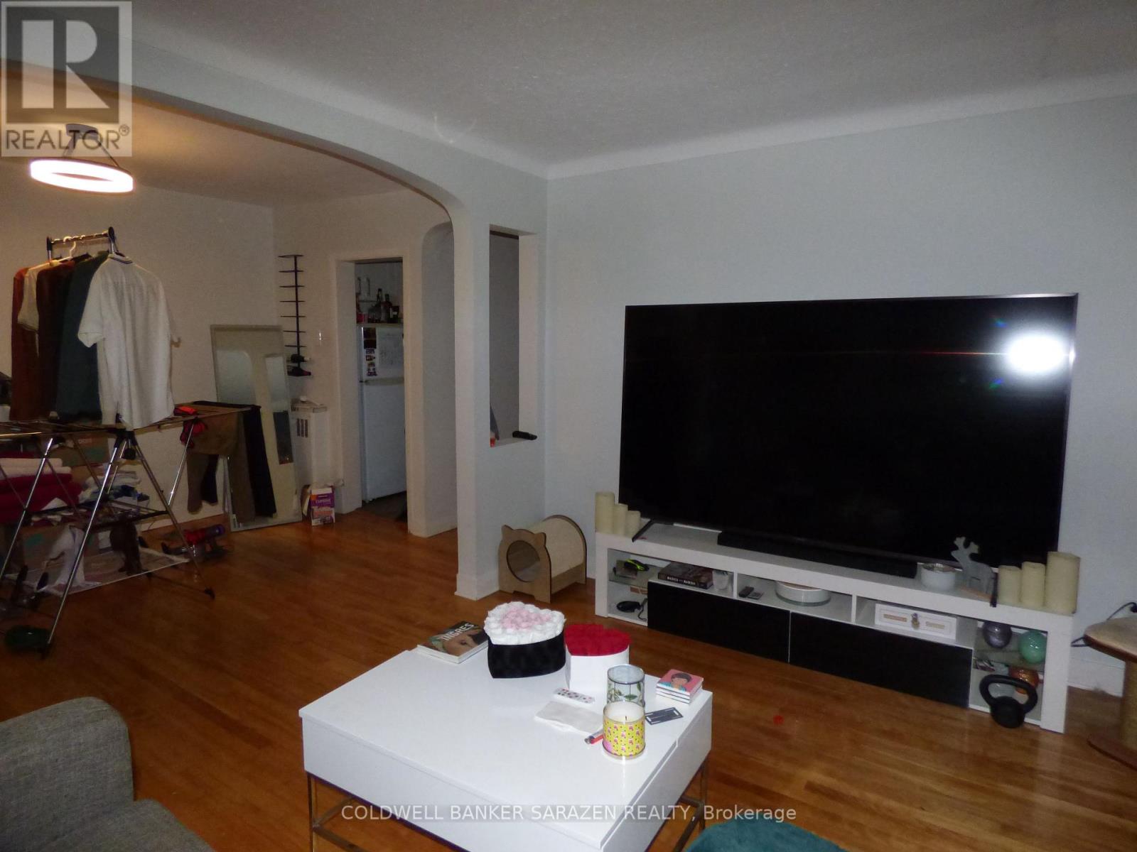 A living room with a white coffee table and a black television.