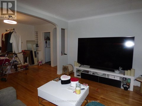 A living room with a white coffee table and a black television.
