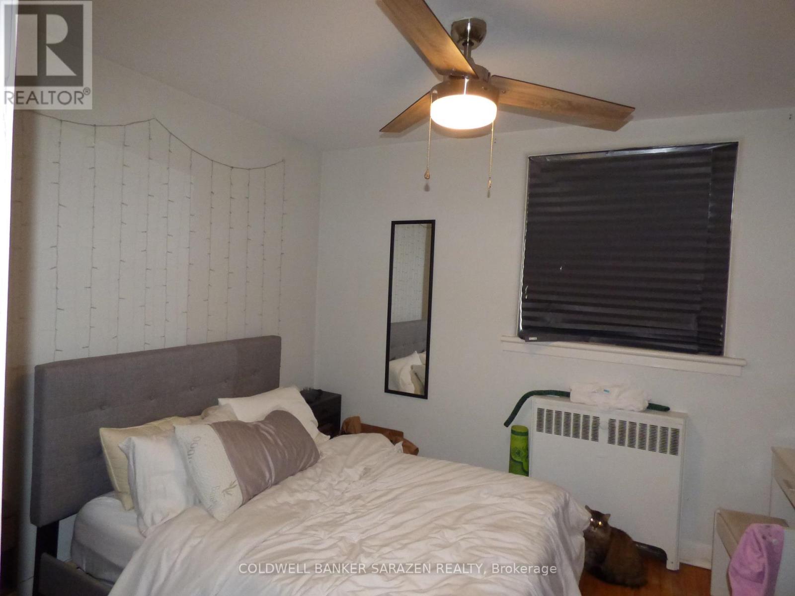 A bedroom with a bed, a ceiling fan, and a window with blinds.