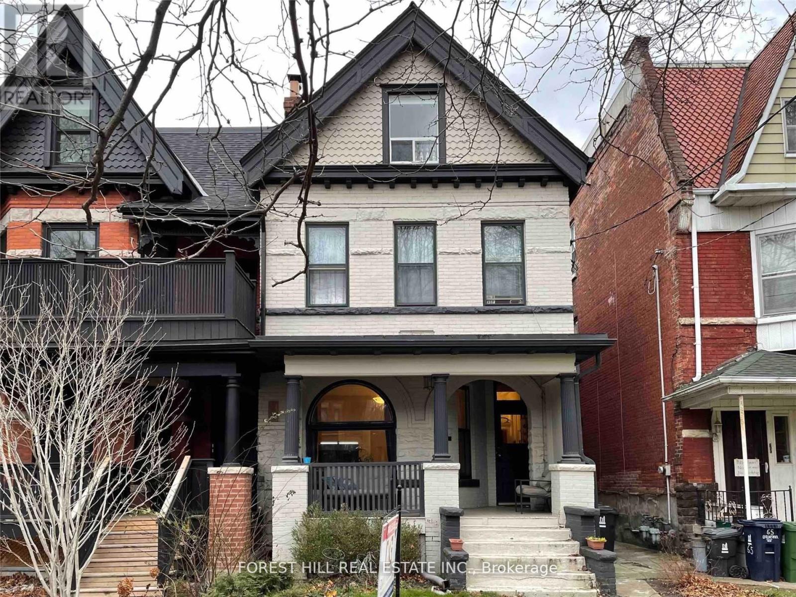 A house with a porch and a sign that says Forest Hill Real Estate Inc. Brokerage.