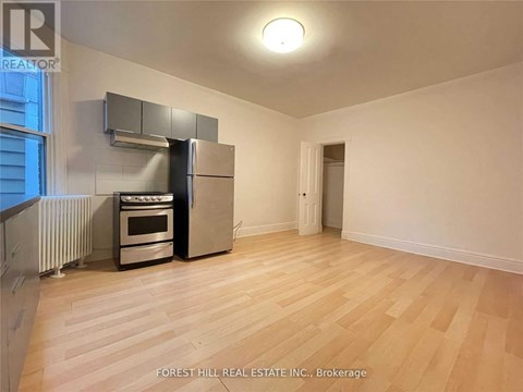 A kitchen with a stove, oven, and refrigerator in a white room.