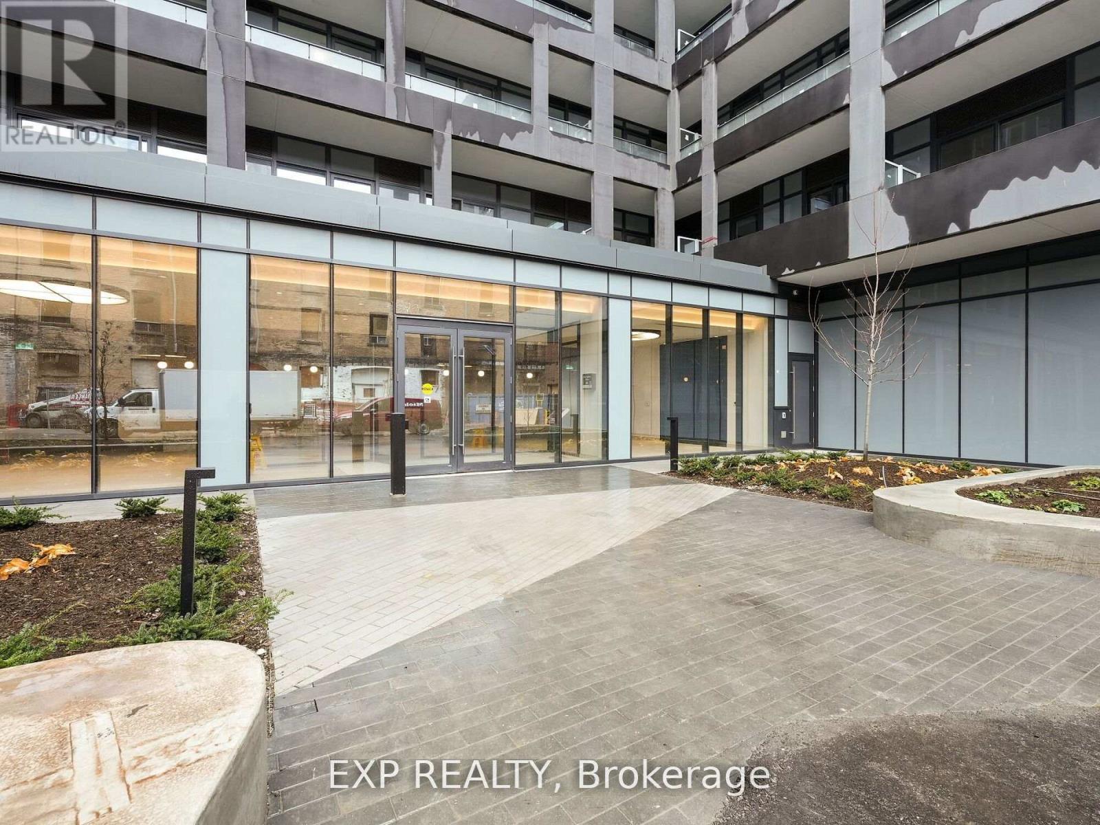 A modern building entrance with glass doors and a brick walkway.