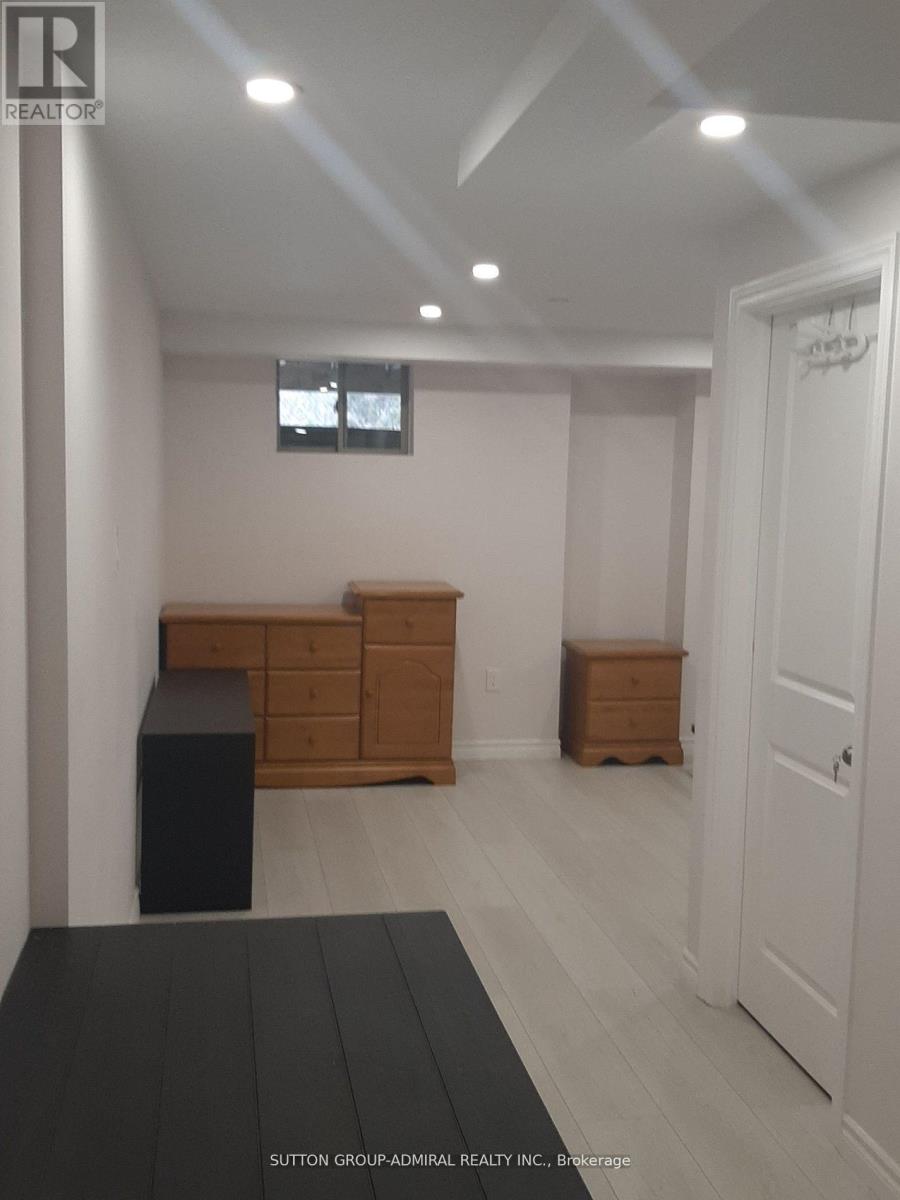 A room with a black rug on the floor and a wooden dresser.