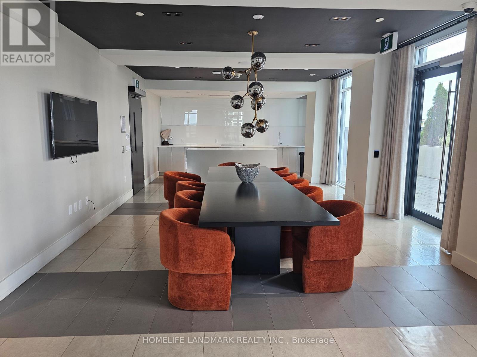 A modern dining room with a black table and orange chairs.
