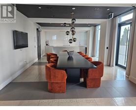A modern dining room with a black table and orange chairs.