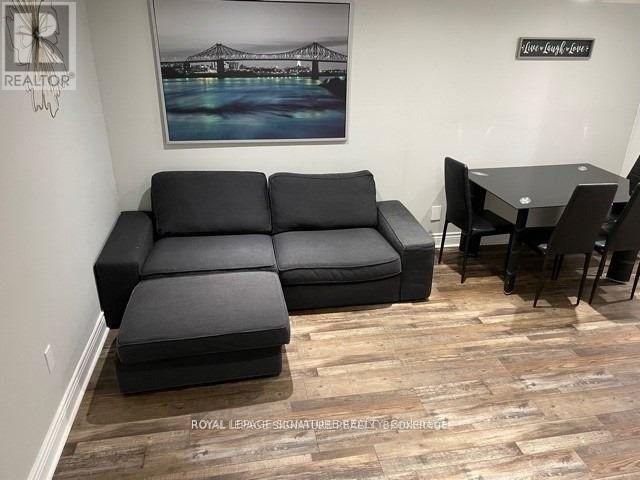 A living room with a black sofa and a wooden floor.