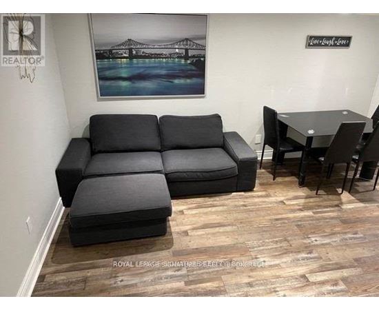 A living room with a black sofa and a wooden floor.