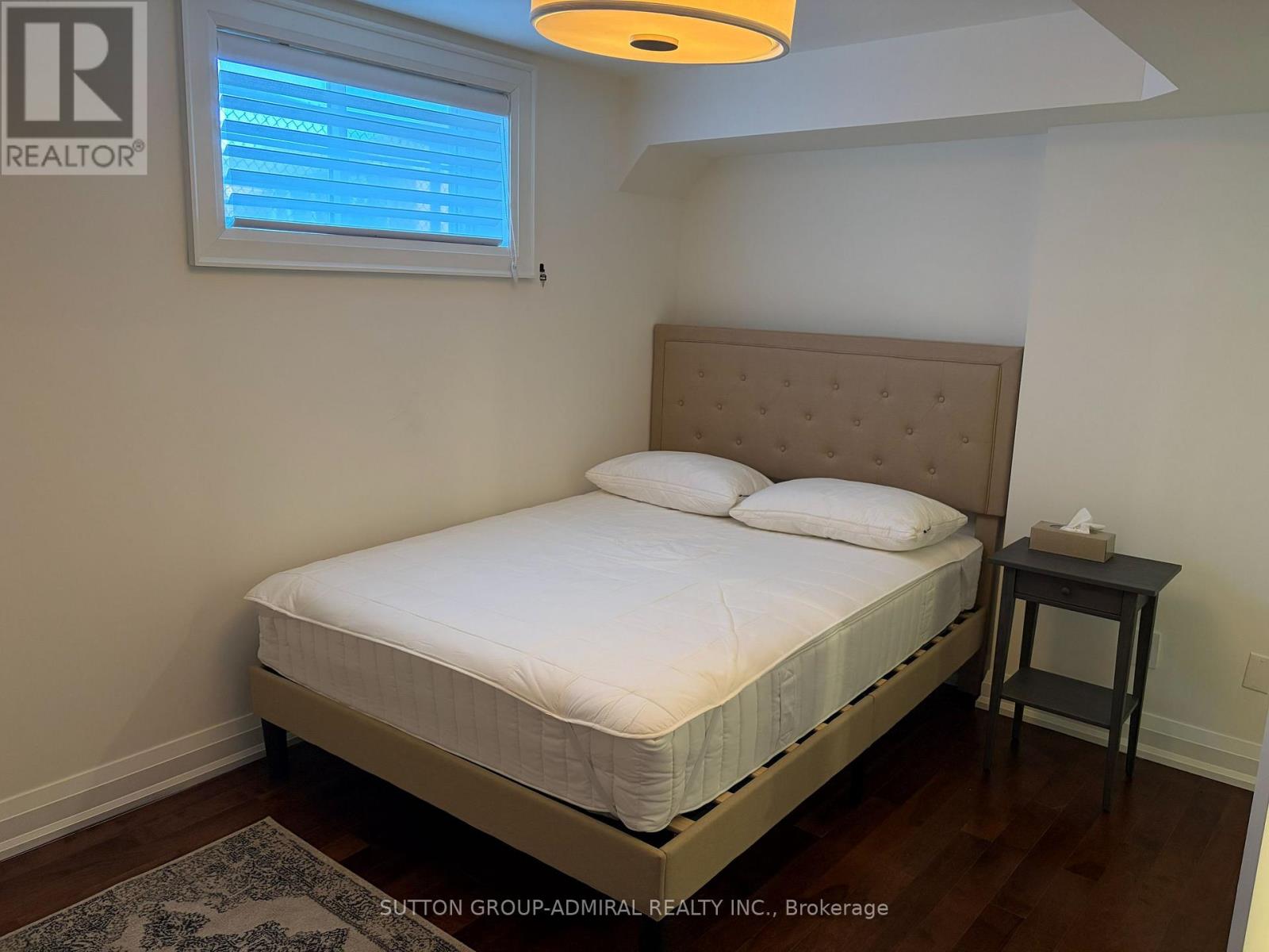 A bedroom with a bed, nightstand, and window.