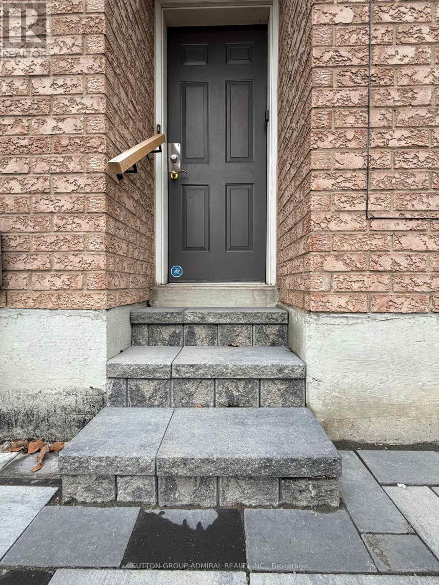 A black door with a brass handle is on a brick wall.