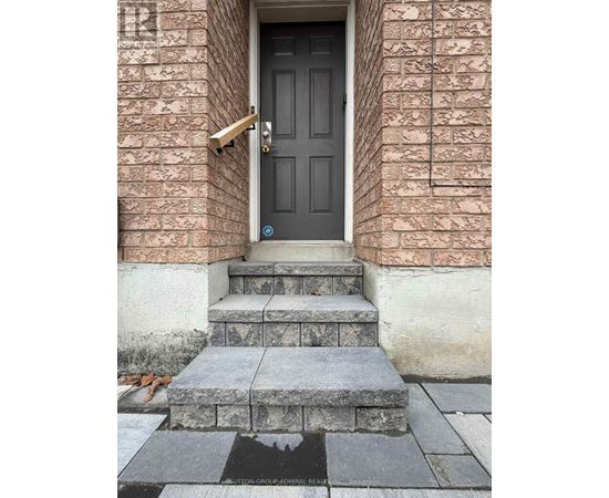 A black door with a brass handle is on a brick wall.