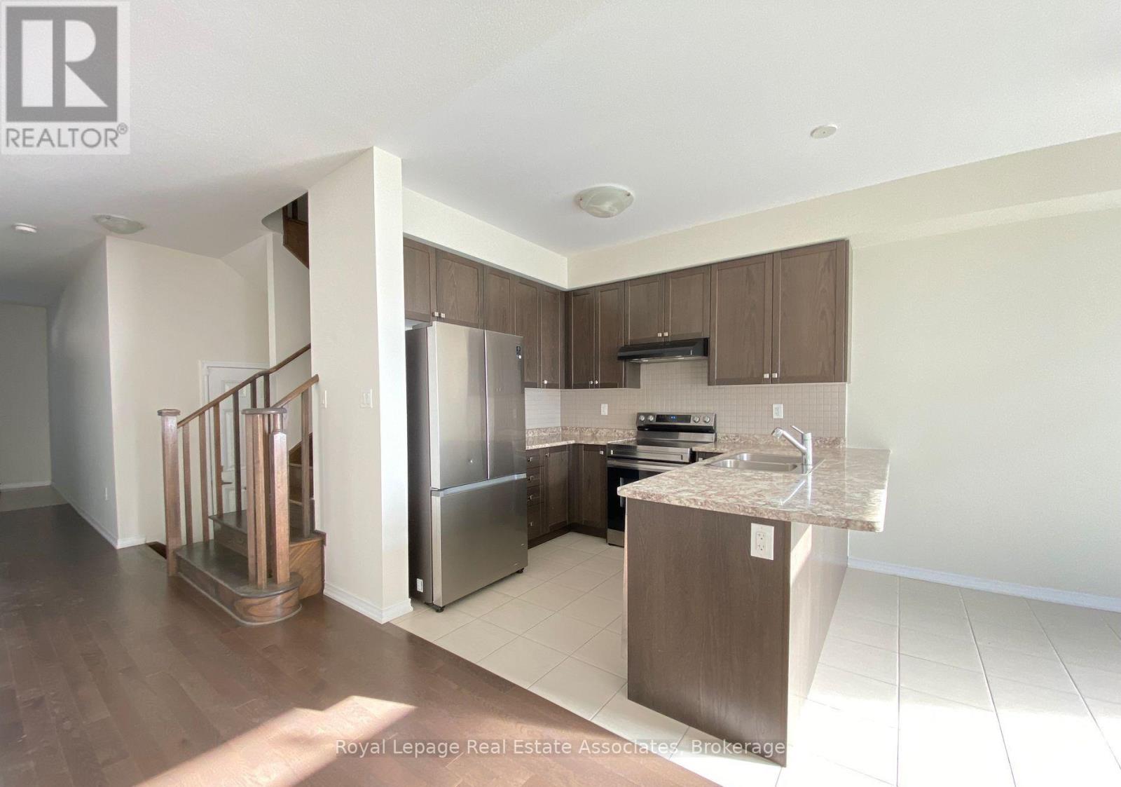 A modern kitchen with a refrigerator, sink, and cabinets.