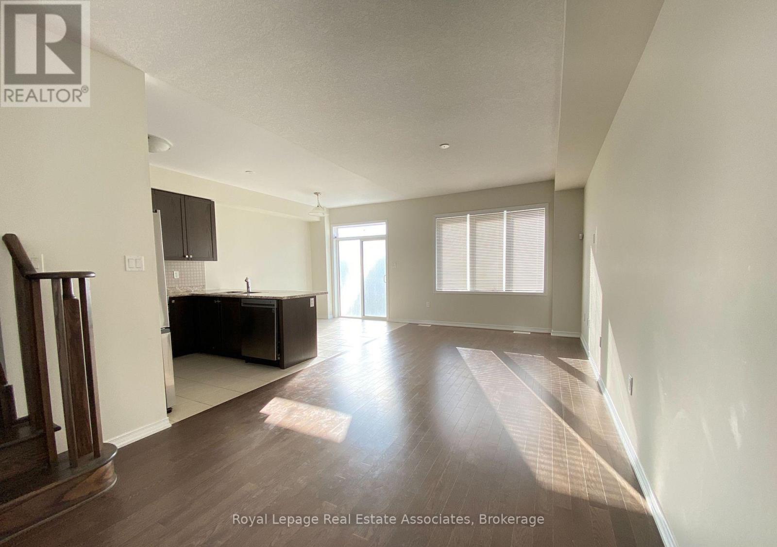 A spacious room with wooden floors and a large window.