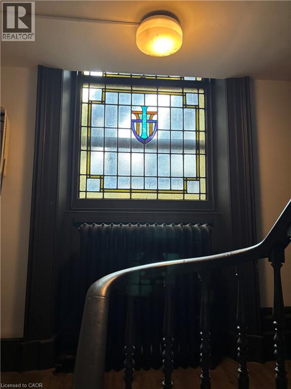 A stained glass window with a shield design is in a dark room.