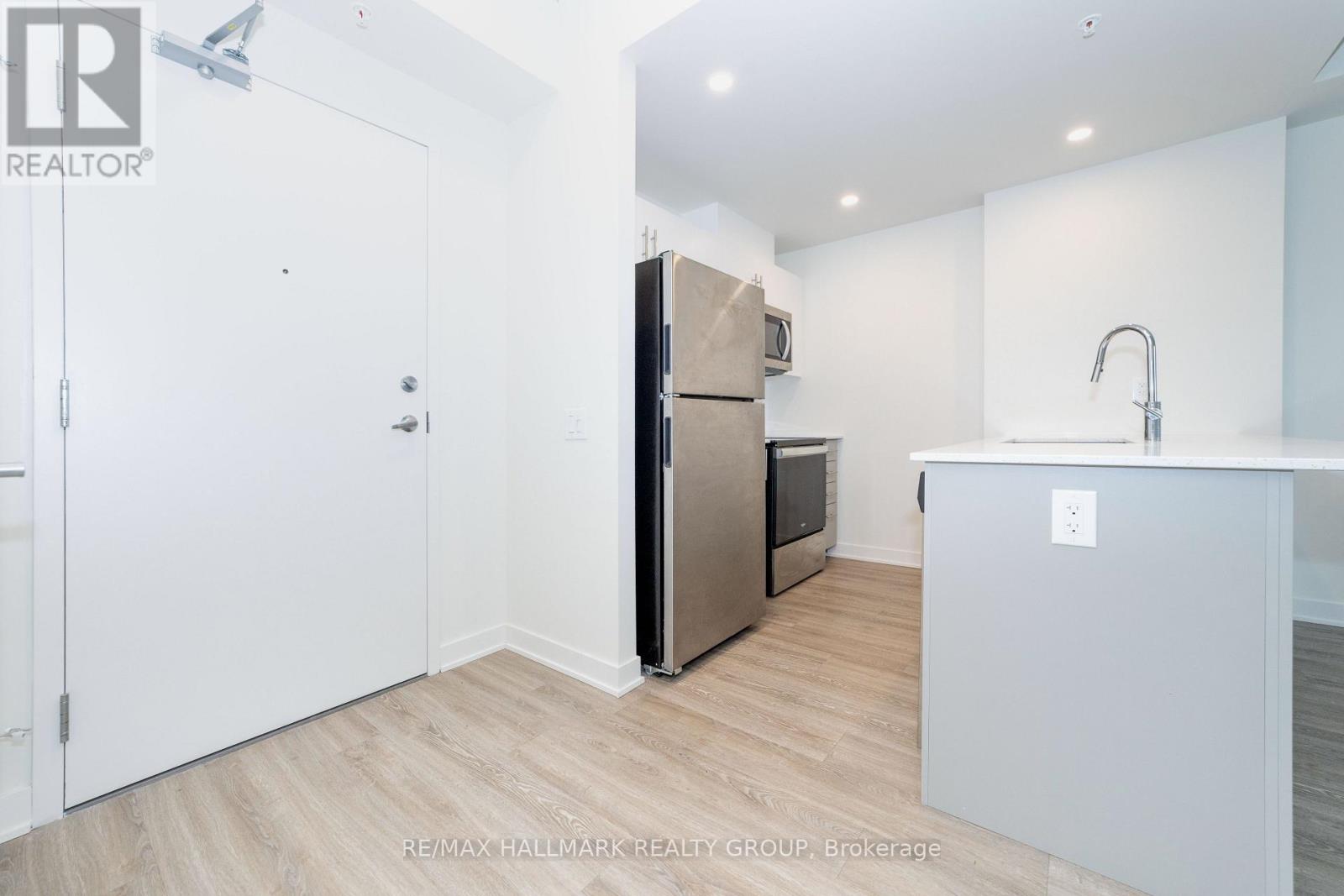 A kitchen with a refrigerator, sink, and cabinets.