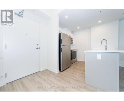 A kitchen with a refrigerator, sink, and cabinets.