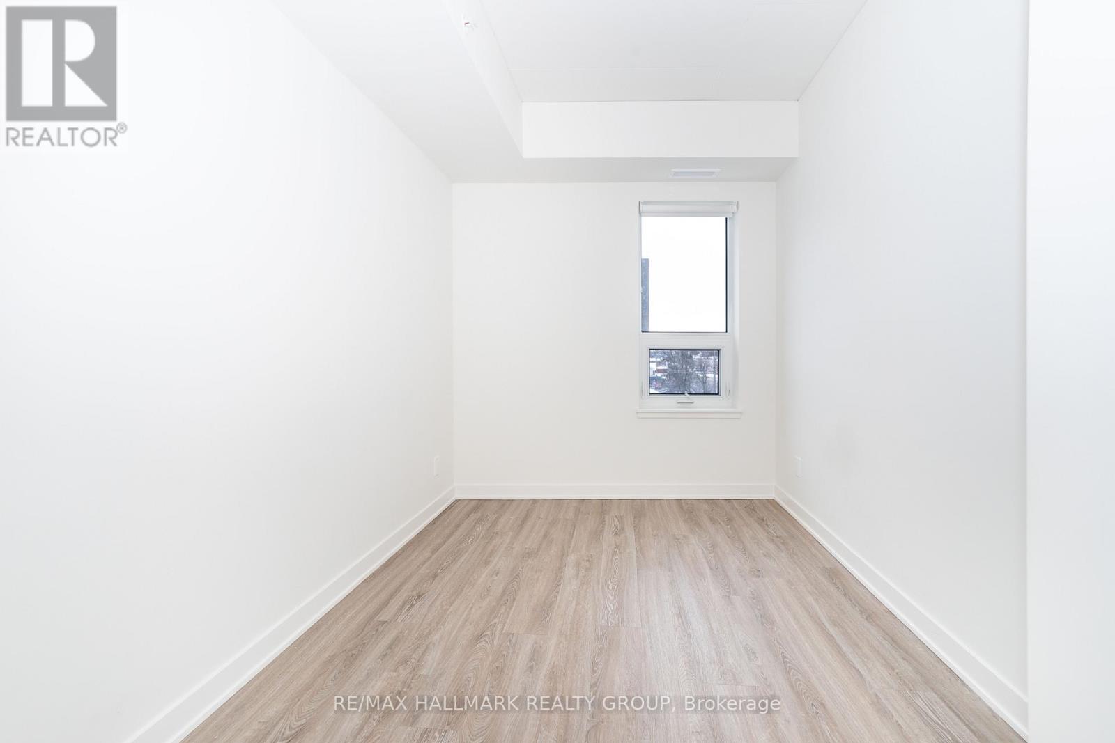 A white room with a window and a wooden floor.