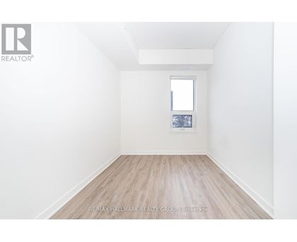 A white room with a window and a wooden floor.