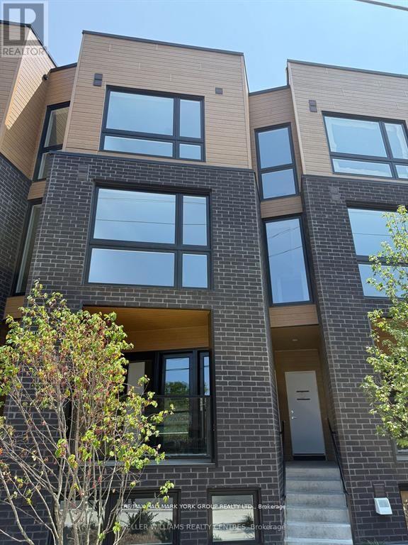 A modern brick building with large windows and a clear sky in the background.