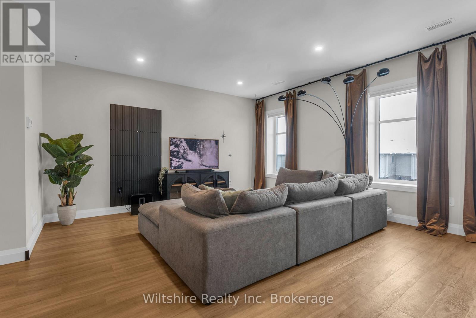 A living room with a grey couch and a plant.