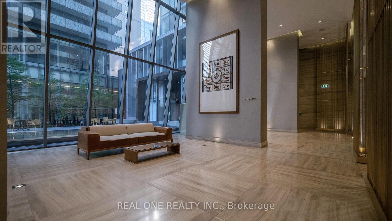 A modern office lobby with a wooden bench and a framed picture on the wall.