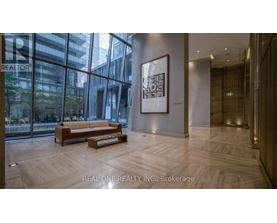 A modern office lobby with a wooden bench and a framed picture on the wall.