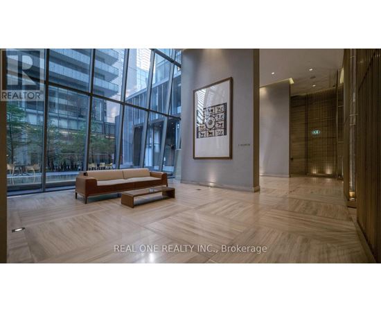 A modern office lobby with a wooden bench and a framed picture on the wall.