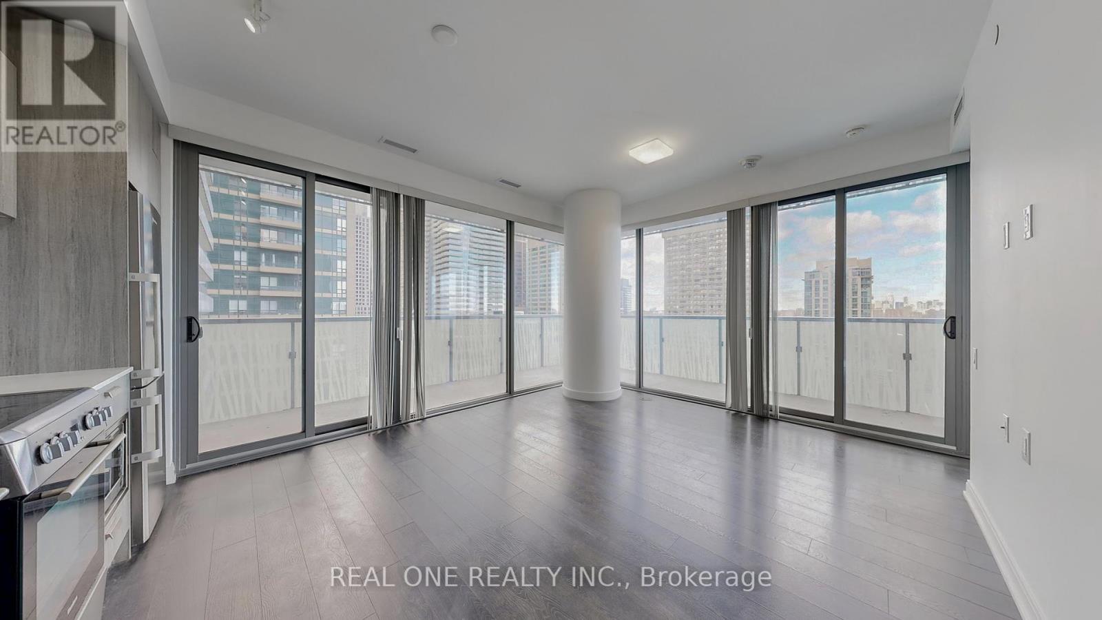A spacious, empty room with large windows and sliding glass doors.